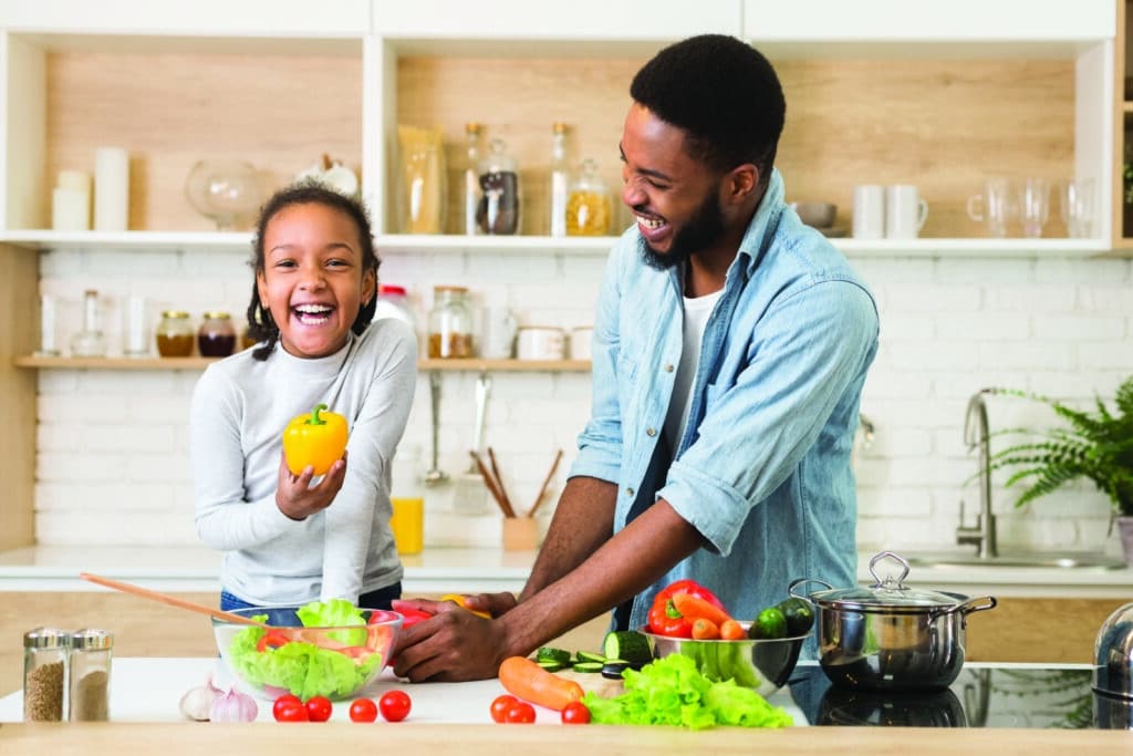 Cute,Cheerful,Girl,Holding,Pepper,While,Helping,Dad,Cooking,Dinner